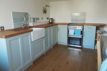 Photo of kitchen with wooden work tops, oak floors, painted wooden cabinets and a butler sink.
